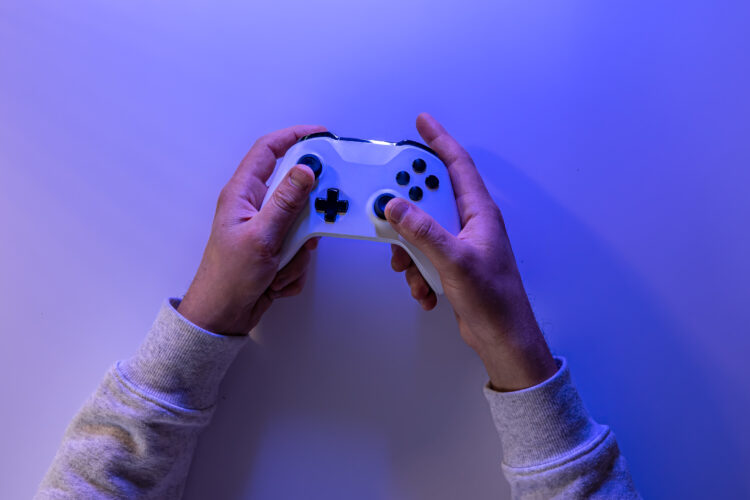 Male hands hold a gamepad on a blue background, copy space.
