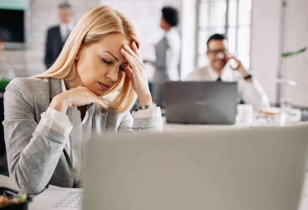 Businesswoman experiencing a strong headache while working in the office.